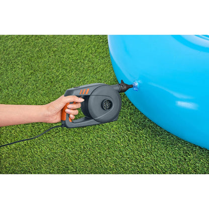 Hand using a black and orange air pump to inflate a blue pool on grass
