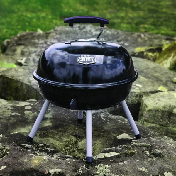 Black portable grill with a brand logo on a rocky surface