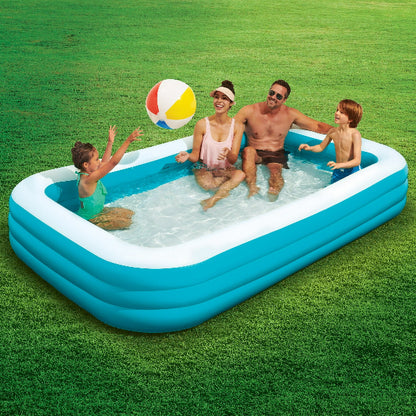 Family playing with a beach ball in an inflatable pool on grass